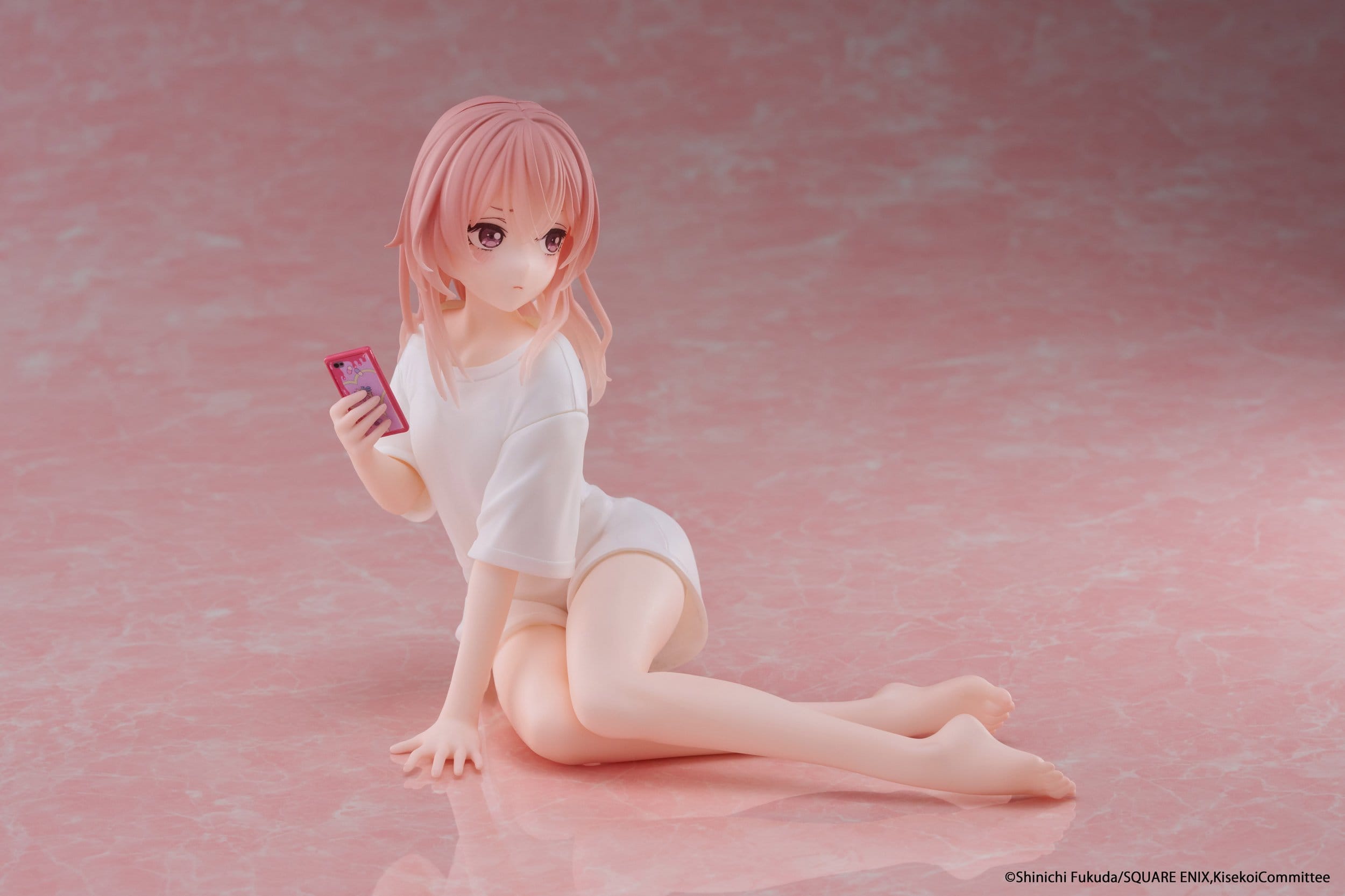 The Taito Desktop Cute Sajuna Inui T-shirt Ver. PVC Figure (13 cm) features Sajuna from My Dress-Up Darling, seated on a pink marbled base with pink hair, a loose white t-shirt, and holding a pink smartphone, looking thoughtfully to the side.