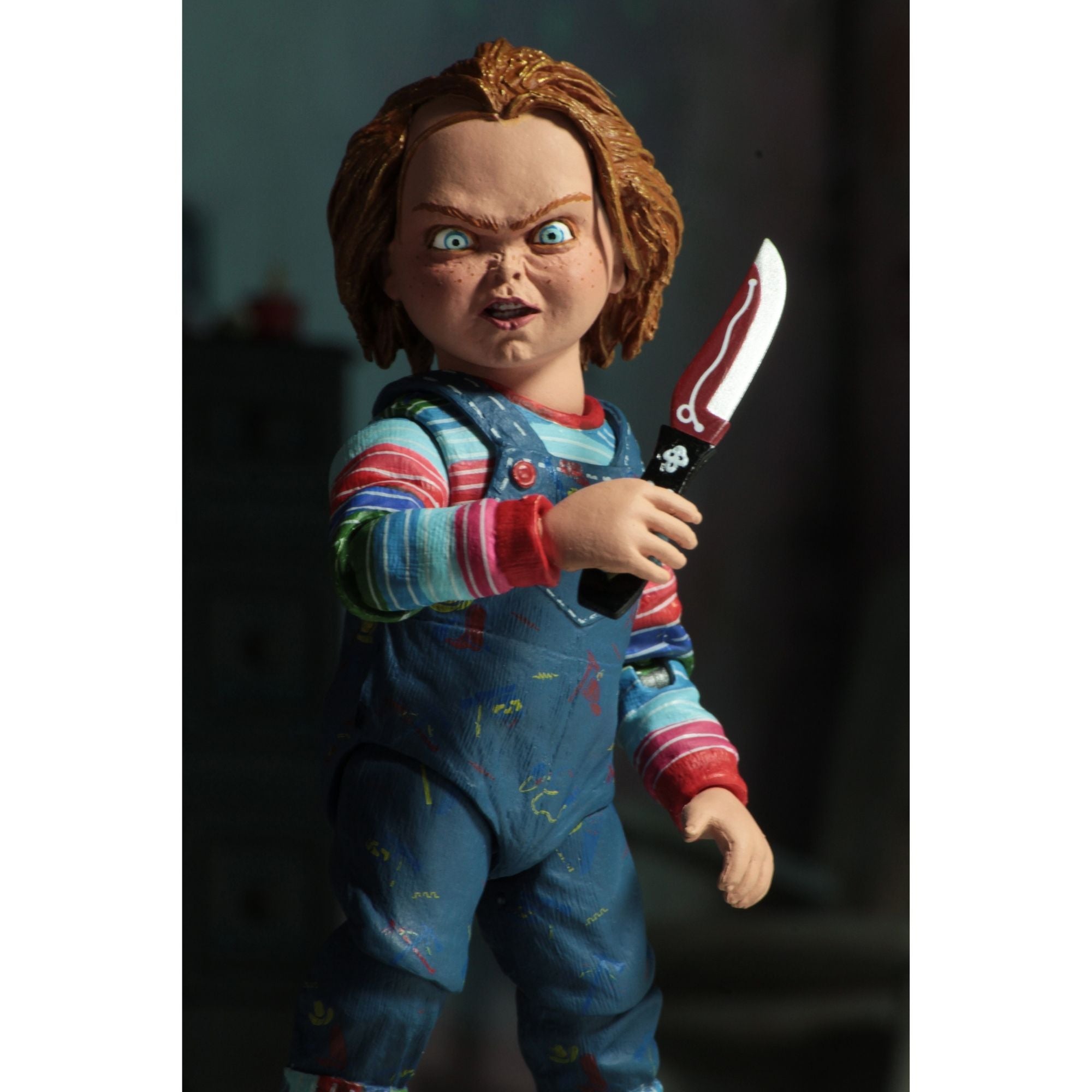 The NECA Child's Play Ultimate Chucky Action Figure (4 inch) by NECA features Chucky with messy brown hair, blue overalls, a striped shirt, and a large red and silver knife, complete with menacing wide blue eyes.