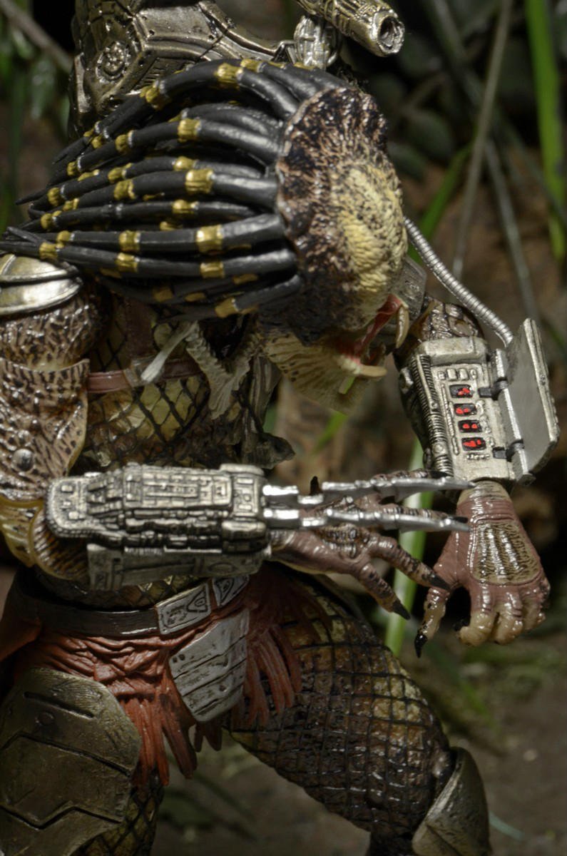 The NECA Predator Jungle Hunter Ultimate Action Figure (7 inch) features detailed armor, mechanical wrist blades, and dreadlock-like hair, posed in a jungle setting with foliage in the background.