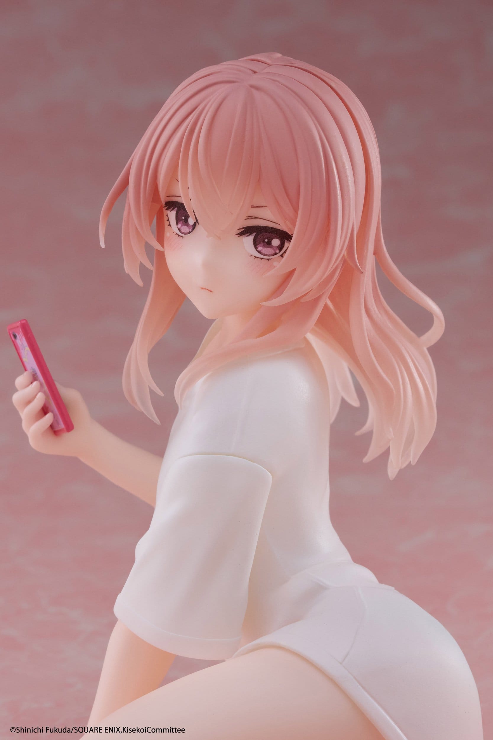 The Taito Desktop Cute Sajuna Inui T-shirt Ver. PVC Figure (13 cm) by Taito features a pink-haired anime character with large purple eyes, in a loose white shirt, holding a pink smartphone against a soft pink background.