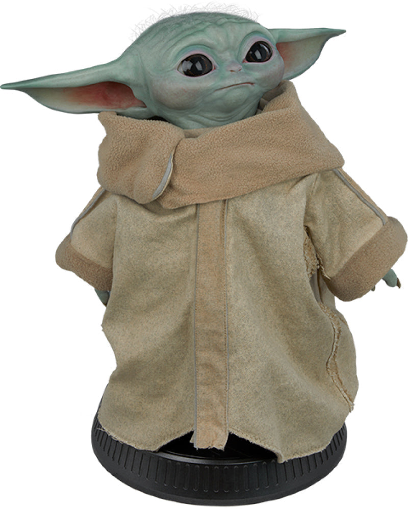 The Sideshow Collectibles Star Wars: The Mandalorian – The Child Life-Size Figure (1:1 Scale) by Sideshow features Grogu in a tan robe on a black base, making it an ideal addition to any Star Wars fan’s collection.